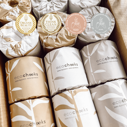 A box of eco:cheeks Zero Bleach 100% Bamboo Shampoos, showing multiple wrapped bottles in gold, white, and gray packaging with bamboo leaf patterns and award seals.